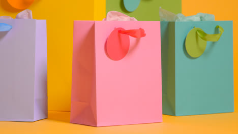 Studio-Shot-Of-Colourful-Birthday-Party-Gift-Bags-Against-Yellow-Background